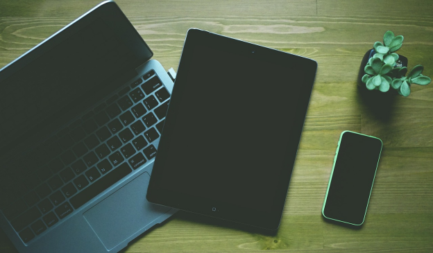 A smartphone next to a tablet and laptop