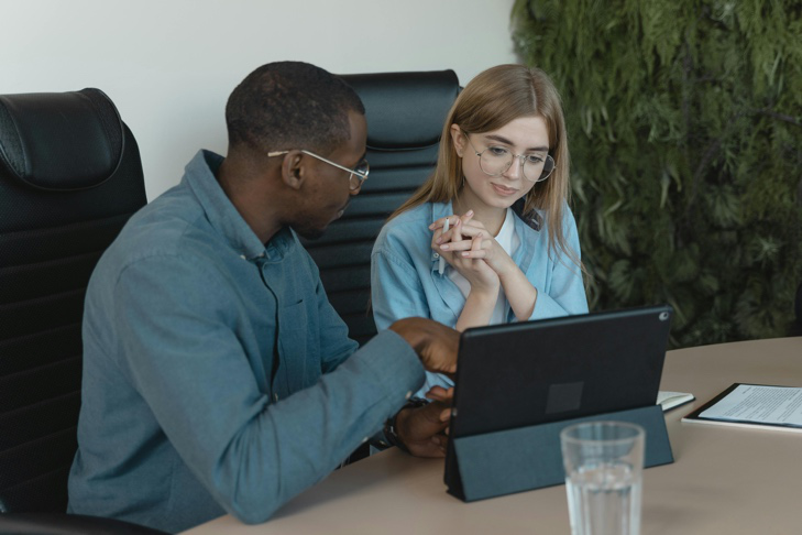 A Man Teaches a Woman Using a Laptop.